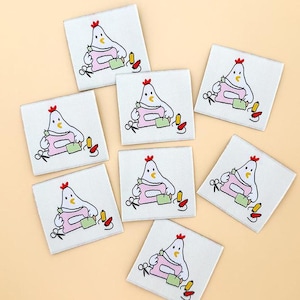 May include: A collection of white square fabric labels featuring a cartoon chicken sewing with a pink sewing machine. Each label includes scissors, spools of thread, and a green fabric piece. The chicken has a red comb.