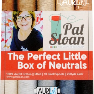 Puede incluir: Una caja de 10 pequeñas bobinas de hilo de algodón Aurifil 50wt en colores neutros. La caja está etiquetada como "The Perfect Little Box of Neutrals" y presenta una foto de Pat Sloan, "The Voice of Quilting".