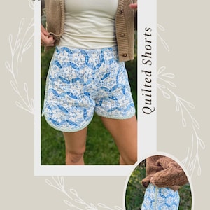 Könnte beinhalten: Gesteppte Shorts mit blau-weißem Blumenmuster. Die Shorts haben einen Kordelzug in der Taille und sind mit einer hellblauen Bordüre versehen. Das Bild enthält auch den Text "Quilted Shorts".