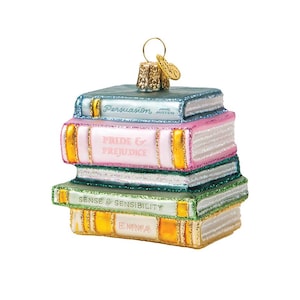 May include: A stack of four decorative book ornaments. The books are in shades of blue, pink, and green, with gold accents. The titles "Persuasion", "Pride & Prejudice", "Sense & Sensibility", and "Emma" are visible. A gold-colored cap and loop are at the top.