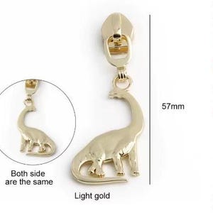 Puede incluir: Tirador de cremallera dorado con un diseño de dinosaurio. El dinosaurio es de color dorado claro y mide 57 mm de alto. Ambos lados del tirador de cremallera son iguales.