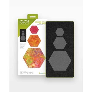 Könnte beinhalten: Eine schwarze Stoffstanzform mit drei Sechseckformen, neben einer Verpackung mit Stoffausschnitten in roten, orangefarbenen und gelben Mustern. Die Verpackung trägt den Text "GO! Fabric Cutting Die" und "HEXAGON-1", 1 1/2" 2 1/2" SIDES".
