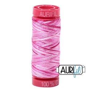 Peut inclure: Une bobine de fil de coton de couleur rose et blanche avec le texte "Aurifil 100% Coton" sur l'étiquette.