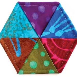 May include: A vibrant, hexagonal fabric coaster. It features six triangular segments, each with a distinct pattern and colour, including teal, purple, blue, brown, green, and red. The edges are stitched with white thread.