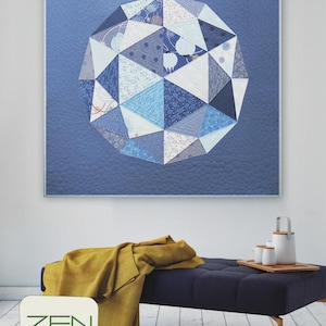 Puede incluir: Un edredón geométrico en tonos azules y blancos cuelga de una pared. El diseño presenta una forma esférica compuesta por triángulos. Una manta amarilla descansa sobre un banco azul oscuro. Los textos "ZEN CHIC" y "GLOBE" son visibles.