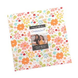 Può includere: Un pacco di tessuto quadrato con un motivo floreale nei toni del rosa, arancione, giallo e blu su sfondo bianco. Il tessuto è etichettato "Moda Fabrics & Supplies" con il testo "Delightfully Yours".