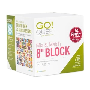 Puede incluir: Una caja blanca con el texto "GO! QUBE" y "Mix & Match 8" BLOCK" en rosa. La caja anuncia la posibilidad de crear más de 72 diseños de bloques e incluye 8 troqueles, una esterilla de corte, un libro de patrones y un DVD paso a paso. El bloque de 20 cm.