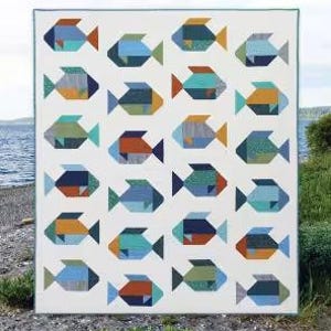 Puede incluir: Un edredón blanco con un patrón repetido de peces coloridos en tonos azules, naranjas y verdes. La palabra "Fish" está en la parte superior y el texto "A fat quarter quilt in 3 sizes" en la parte inferior.