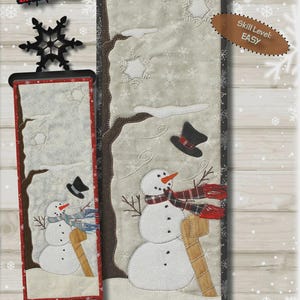 Könnte beinhalten: Stoffpaneel mit Wintermotiv, das einen Schneemann mit Schal und Hut zeigt, sowie den Text "WINDY WINTER". Das Panel misst 16,5 x 45,7 cm. Der Schwierigkeitsgrad ist einfach.