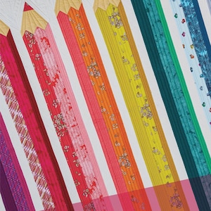 Op de afbeelding: Een kleurrijke quilt met een potloodontwerp. De quilt toont verschillende tinten rood, oranje, geel, groen en blauw, waarbij elk potlood een ander patroon heeft. De tekst "PENCIL CLUB PRESIDENT QUILT" is zichtbaar.