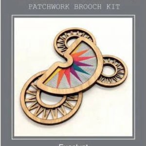 May include: A colourful patchwork brooch kit called "Eucalypt" measuring 2.5 inches by 3.5 inches. The kit features a wooden base with a colourful geometric design.