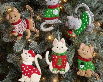 May include: Seven felt cat ornaments featuring different Christmas jumper designs. The cats are in various poses, including sitting, standing, and lying down. The jumpers are decorated with snowflakes, Christmas trees, and other festive designs.