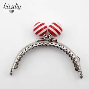 May include: Silver purse frame with red and white striped plastic ball closures.