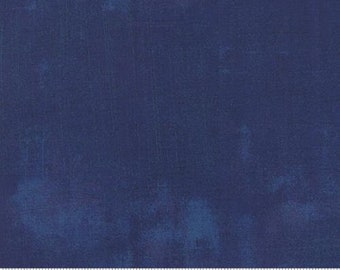 May include: A close-up of a piece of fabric in a deep navy blue colour with lighter blue mottled accents. The fabric has a textured appearance, with subtle variations in colour and tone. A ruler is at the bottom.