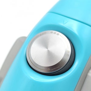 Puede incluir: Primer plano de un cepillo de dientes el&eacute;ctrico azul claro con un bot&oacute;n de encendido plateado etiquetado como "OFF".