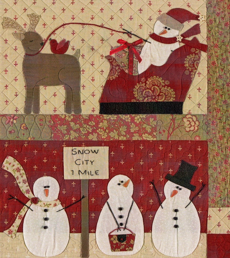 Puede incluir: Un tapiz de pared acolchado con un mu&ntilde;eco de nieve montando en un trineo tirado por un reno. El letrero dice "Snow City 1 Mile".