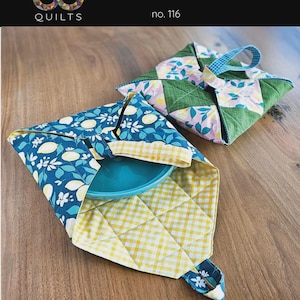 May include: Two quilted pie carriers, each approximately 17 inches by 17 inches flat. One carrier is open, holding a teal plate. The carriers feature blue floral and yellow gingham patterns. The text "Pie Carrier" and "Staci Quilts" are visible.