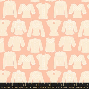 May include: A pink fabric with a repeating pattern of white blouses with different necklines and sleeve lengths. The fabric has a ruler with the text "RUBY STAR SOCIETY" printed on it.