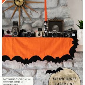 Może przedstawiać: Nowy zestaw do wykonania szalika na kominek w kształcie nietoperza, z pomarańczową tkaniną o wymiarach 60" x 9" z wycięciami w kształcie nietoperzy. Zestaw zawiera laserowo wycięte, topliwe nietoperze. Numer zestawu to SISIQE LX, projekt L. Simona. Zestaw jest dostępny w sprzedaży na windhamfabrics.com.
