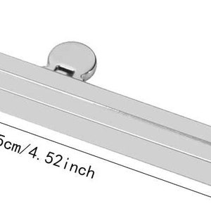 Pode incluir: Estrutura de bolsa de metal prateado com fecho de encaixe. A estrutura mede 11,5 cm de comprimento e 1 cm de largura.