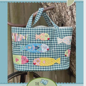 May include: A blue and white gingham tote bag with colorful fish appliqués. The bag has two handles and the text "Kiss Me Quick BAG" is at the top. The Birdhouse Patchwork Designs logo is at the bottom.