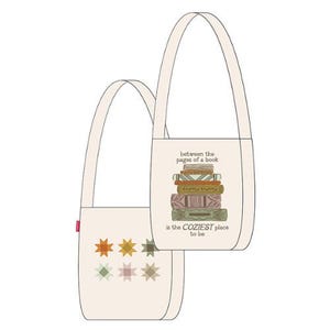 May include: Two off-white tote bags. One bag features a stack of books with the text "between the pages of a book is the COZIEST place to be." The other bag has a pattern of six stars in various colours.