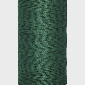 Puede incluir: Un carrete de hilo Gütermann verde oscuro. El carrete es cilíndrico con base y parte superior blancas. El hilo está bien enrollado alrededor del carrete. El texto en la parte superior dice "Gütermann" y en la parte inferior "100 m - 110 yds/vgs".