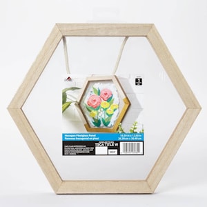 May include: A hexagon-shaped plexiglass panel with a light wood frame. The panel holds a smaller hexagon frame with a floral painting. The dimensions are 10.39 in x 12.00 in. A rope is attached for hanging. The text on the panel reads "Hexagon Plexiglass Panel".