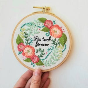 Peut inclure: Broderie florale sur tambour avec l'inscription « this took forever ». Le motif présente des fleurs roses et pêche, des feuilles vertes et un cerceau en bois. Une pièce décorative pour la décoration intérieure.