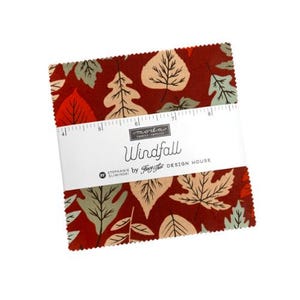 May include: A stack of fabric squares with a leaf pattern in shades of red, beige, and green. The fabric is wrapped with a white band that reads "Windfall" and "Stephanie by Fig Tree Design House."