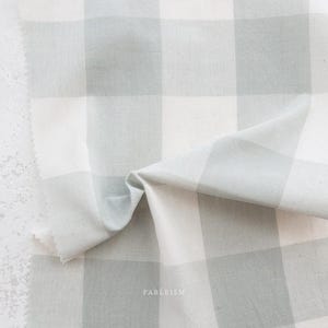 May include: Close-up of a fabric with a large, light gray and white checkered pattern. The fabric is folded, showing the texture and weave. The word "FABLEISM" is printed in the bottom right corner.