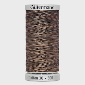May include: A spool of Gütermann brown cotton thread. The spool has a white top with the Gütermann logo and a white base with the text "Cotton 30 • 300 m". The thread is a rich, dark brown colour.