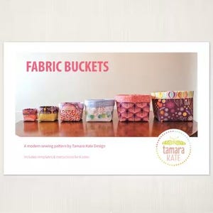 May include: A sewing pattern for fabric buckets, with a title that reads "FABRIC BUCKETS". The pattern includes templates and instructions for six sizes. The image shows six fabric buckets in different sizes and patterns, with a logo for "tamara KATE" at the bottom.