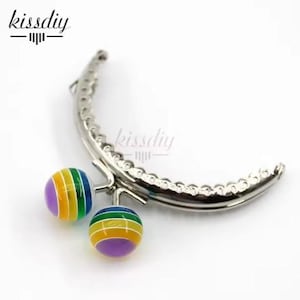 May include: Silver purse frame with two colorful round clasps. The clasps have a rainbow pattern with purple, yellow, green, and blue stripes.