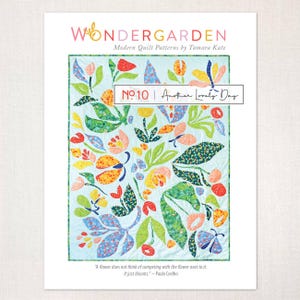 May include: A quilt pattern by Tamara Kate, titled "Wondergarden", with a floral design in red, orange, yellow, and blue, and green leaves on a light blue background. The text "No. 10 | Another Lovely Day" is displayed.