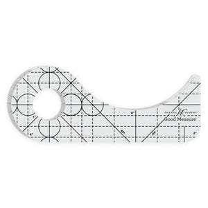 May include: A clear acrylic quilting ruler with a curved edge and a circular cutout. The tool features black printed grid lines, degree markings, and the text Amanda Murphy Good Measure. It includes measurements in inches for precise fabric cutting.