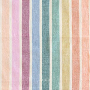 Può includere: Primo piano di un tessuto con strisce verticali dai colori pastello. Le strisce si alternano tra pesca, rosa, bordeaux, azzurro, verde acqua, giallo e pesca. Strisce bianche separano le strisce colorate. La parola "BLEISN" è visibile in basso a destra.