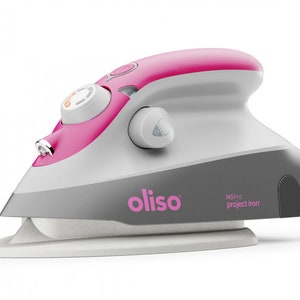 Peut inclure: Un fer à repasser manuel rose et gris avec une base blanche. Le fer possède un cadran de réglage de la température et un bouton pour la vapeur. Le fer est marqué "oliso M3 Pro project iron".