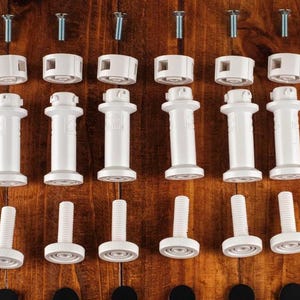 May include: White plastic furniture leg connectors with screws. The connectors have a round top and a cylindrical base. The screws are silver.