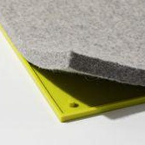 May include: A rectangular lime green plastic base with a small circular protrusion in the corner, partially covered by a thick, textured gray felt pad. The felt layer has a visible thickness and a mottled surface texture, contrasting with the smooth plastic.