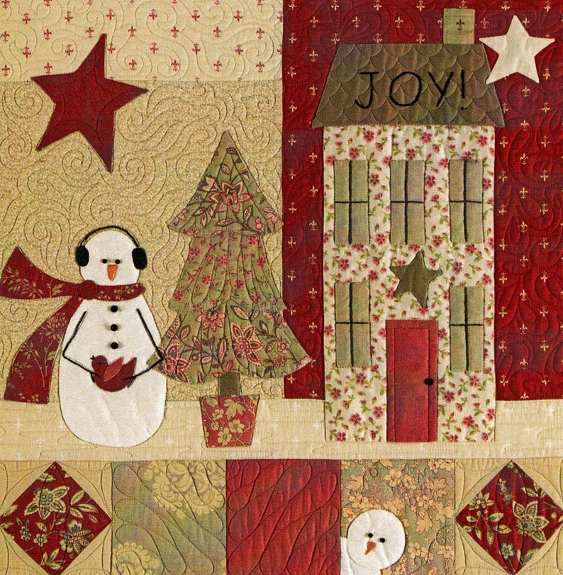 Puede incluir: Un tapiz de pared acolchado con tem&aacute;tica navide&ntilde;a con un mu&ntilde;eco de nieve, un &aacute;rbol de Navidad, una casa con la palabra "ALEGR&Iacute;A" en ella y una estrella roja. El fondo es una tela acolchada beige y roja.