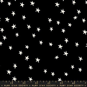 Può includere: Tessuto nero con un motivo a stelle bianche. Le stelle sono di dimensioni diverse e sono sparse casualmente sul tessuto.