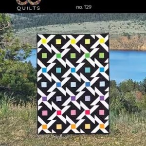 May include: A black and white quilt with a geometric design featuring colourful squares. The quilt is displayed outdoors with the text "PIVOTING" and "no. 129". Finished size is 115.6 cm x 161.3 cm.
