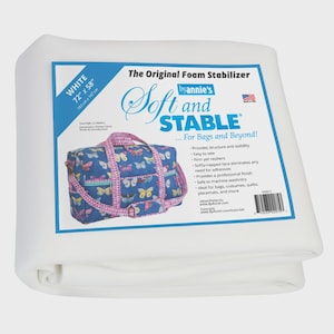 Puede incluir: Rollo de estabilizador de espuma blanco, 183 cm x 147 cm, con una etiqueta azul con una bolsa con estampado de mariposas. La etiqueta dice "Soft and STABLE" y enumera características. Ideal para bolsos, disfraces y edredones.