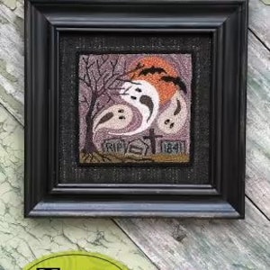 May include: A framed punchneedle embroidery titled "Spooktacular Night" features a Halloween scene with ghosts, a tree, and a tombstone. The artwork is set against a purple and orange background, with the text "RIP" visible. The frame is black.