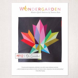 May include: A quilt pattern by Tamara Kate, "Wondergarden", showcases a geometric maple leaf design. The leaf is made of colourful triangles in red, pink, orange, green, and blue against a dark grey background. The text "No. 12 | On Canada!" is also visible.