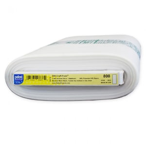 Może przedstawiać: Biała rolka stabilizującej tkaniny Pellon Craft-Fuse 808. Etykieta zawiera napis "808 Craft-Fuse", "Crafts & Home Decor - Stabilizers", "90% Polyester/10% Rayon", "Machine Wash Warm. Tumble dry medium or dry clean", "www.PellonProjects.com", "808", "20 IN 2012", "MADE IN USA".
