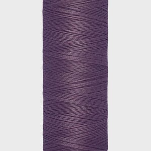 Op de afbeelding: Een spoel Gütermann-garen in een dieppaarse kleur. Het etiket geeft 100 meter garen aan. De draad is strak opgerold, wat de textuur en kleur laat zien. Ideaal voor naai- en knutselprojecten.