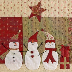 Puede incluir: Tres mu&ntilde;ecos de nieve blancos con sombreros y bufandas rojas se encuentran frente a un fondo estampado rojo y verde. Una estrella dorada cuelga sobre ellos. Los mu&ntilde;ecos de nieve tienen ojos negros y botones. Un mu&ntilde;eco de nieve tiene una bufanda roja, otro una bufanda verde y el &uacute;ltimo una bufanda marr&oacute;n.