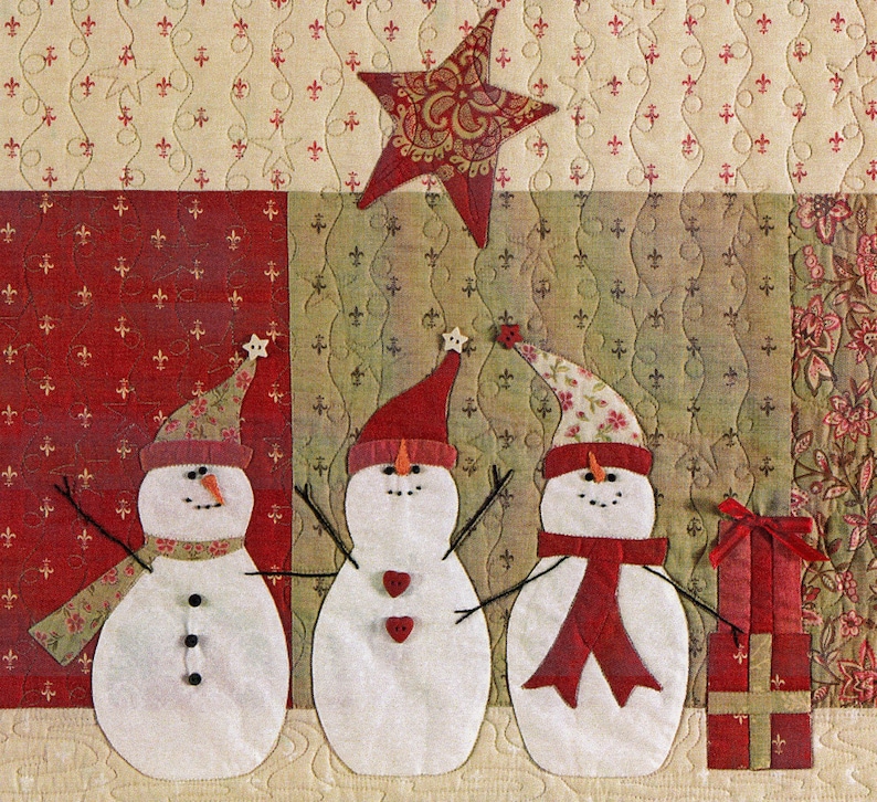 Puede incluir: Tres mu&ntilde;ecos de nieve blancos con sombreros y bufandas rojas se encuentran frente a un fondo estampado rojo y verde. Una estrella dorada cuelga sobre ellos. Los mu&ntilde;ecos de nieve tienen ojos negros y botones. Un mu&ntilde;eco de nieve tiene una bufanda roja, otro una bufanda verde y el &uacute;ltimo una bufanda marr&oacute;n.